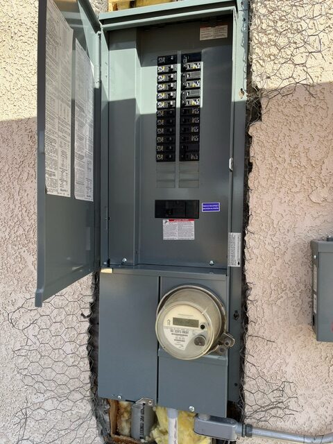 A gray electrical panel with an electric meter on the side.